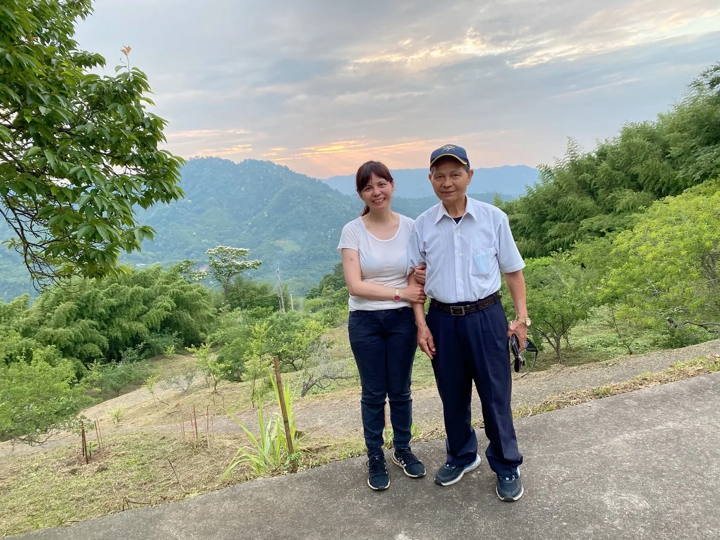 Yaba 與 Maya 在山上並肩合影，身後是層層山谷與夕陽
