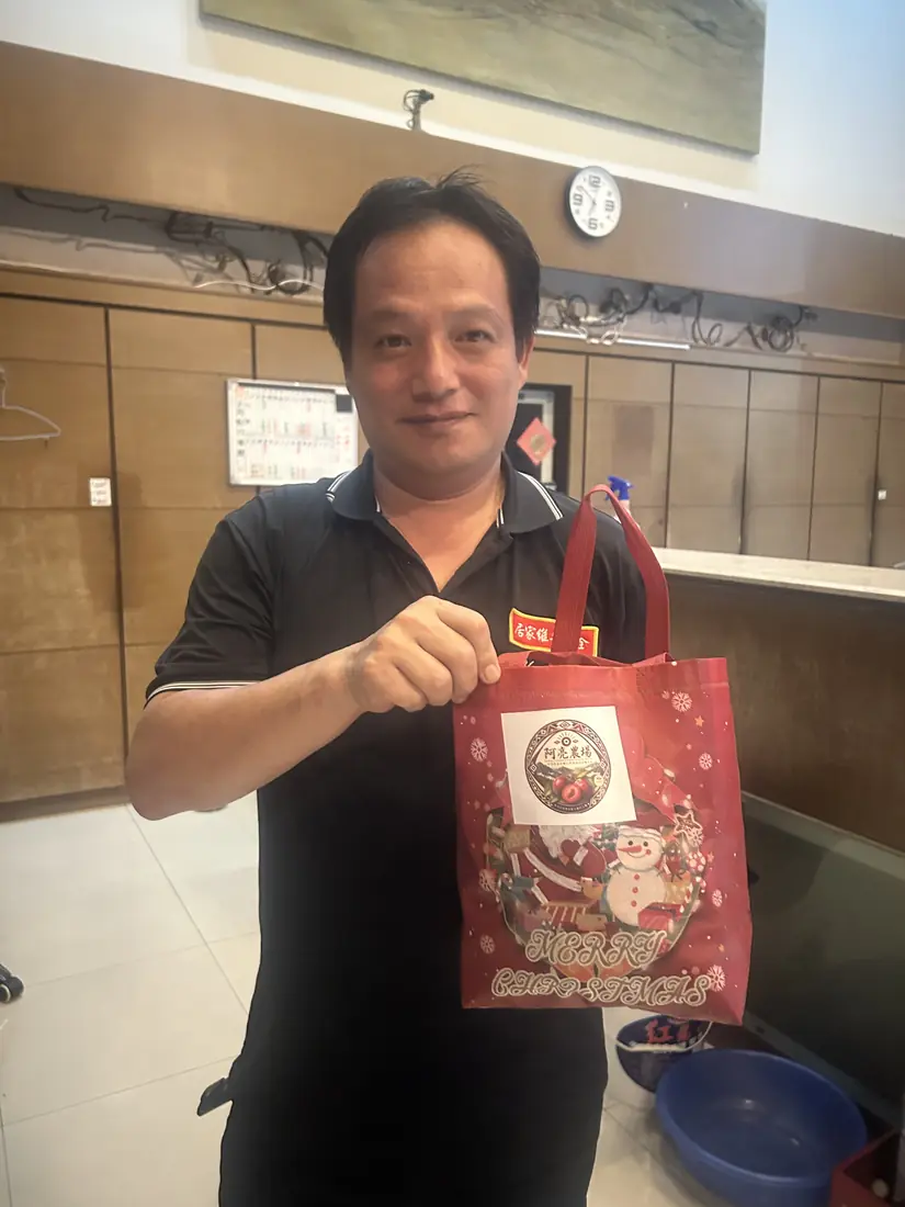A friend who received red-flesh plums, smiling and holding a box with the Saluwan Farm label