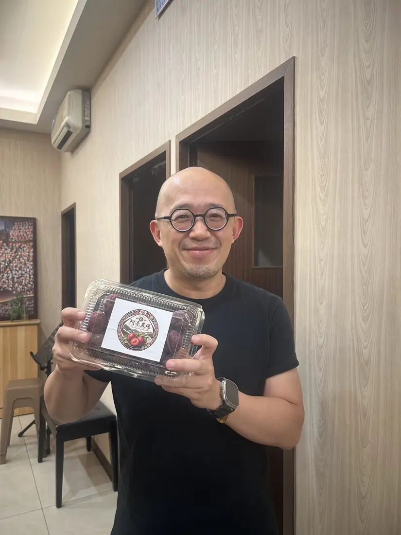 A friend who received red-flesh plums, smiling and holding a box with the Saluwan Farm label