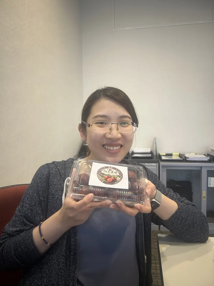 A friend who received red-flesh plums, smiling and holding a box with the Saluwan Farm label