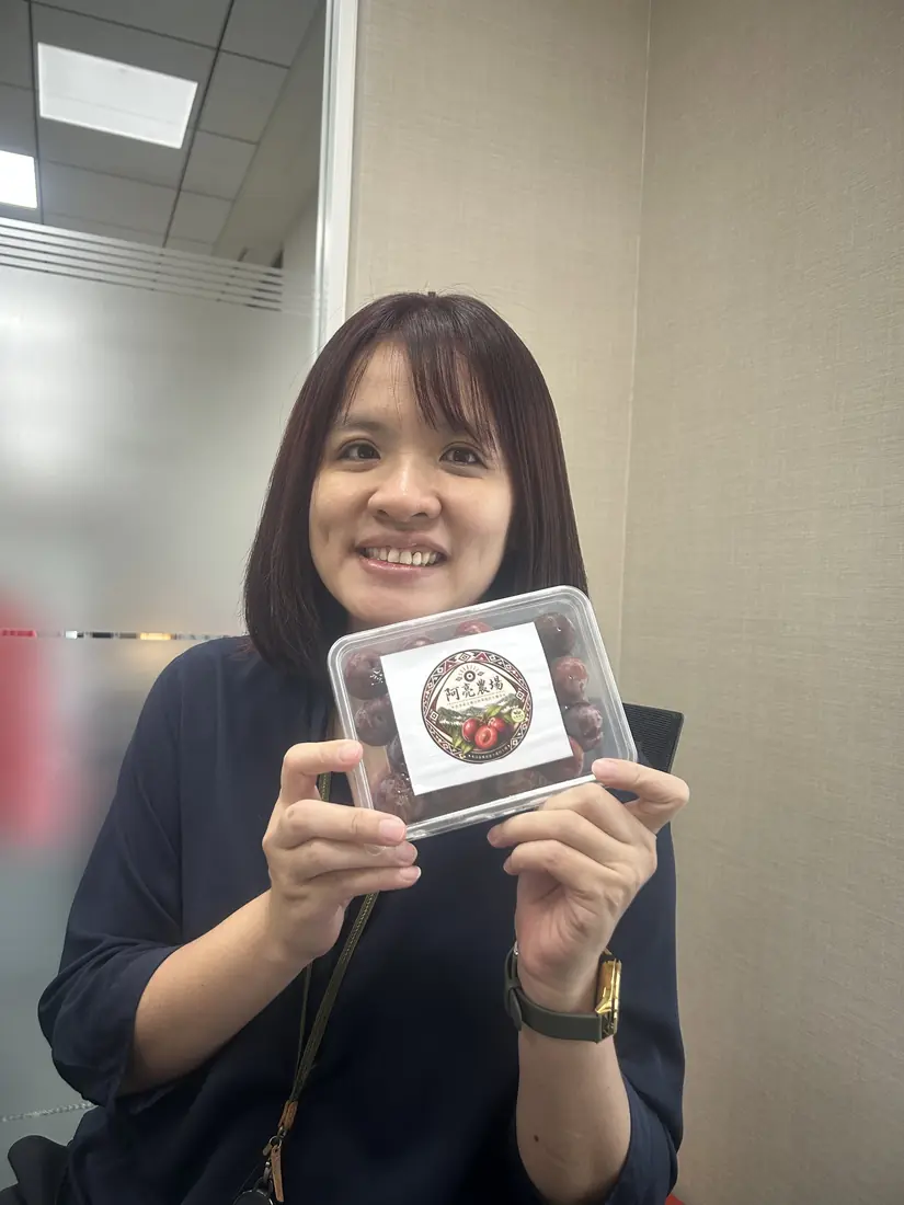 A friend who received red-flesh plums, smiling and holding a box with the Saluwan Farm label