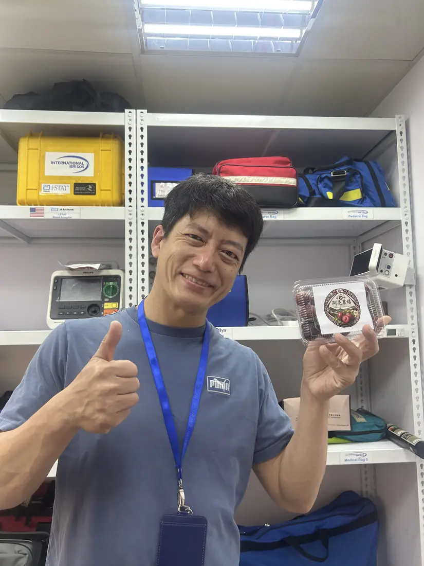 A friend who received red-flesh plums, smiling and holding a box with the Saluwan Farm label