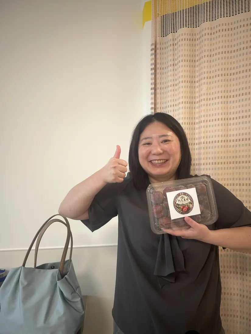 A friend who received red-flesh plums, smiling and holding a box with the Saluwan Farm label