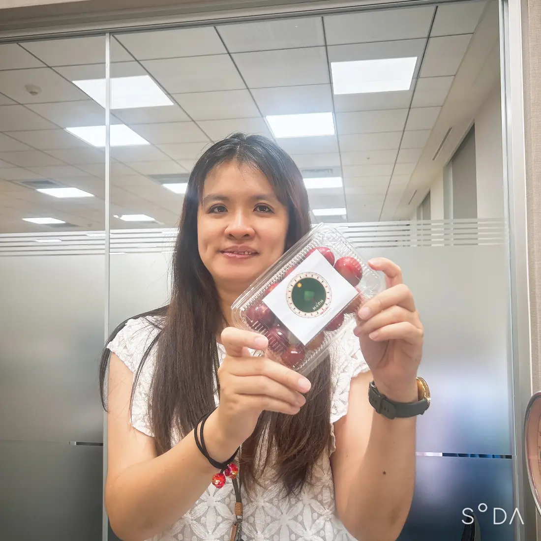 A friend who received red-flesh plums, smiling and holding a box with the Saluwan Farm label