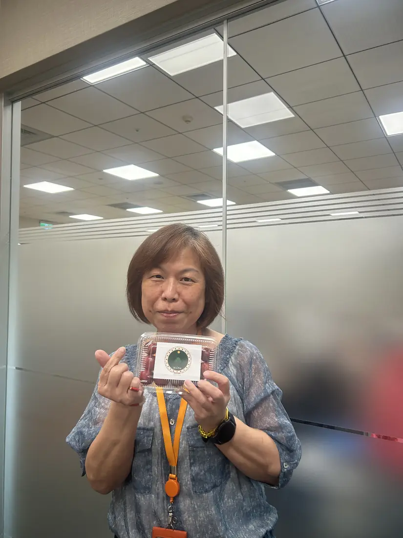 A friend who received red-flesh plums, smiling and holding a box with the Saluwan Farm label