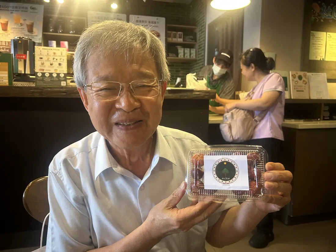A friend who received red-flesh plums, smiling and holding a box with the Saluwan Farm label