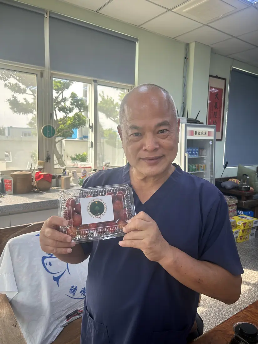 A friend who received red-flesh plums, smiling and holding a box with the Saluwan Farm label
