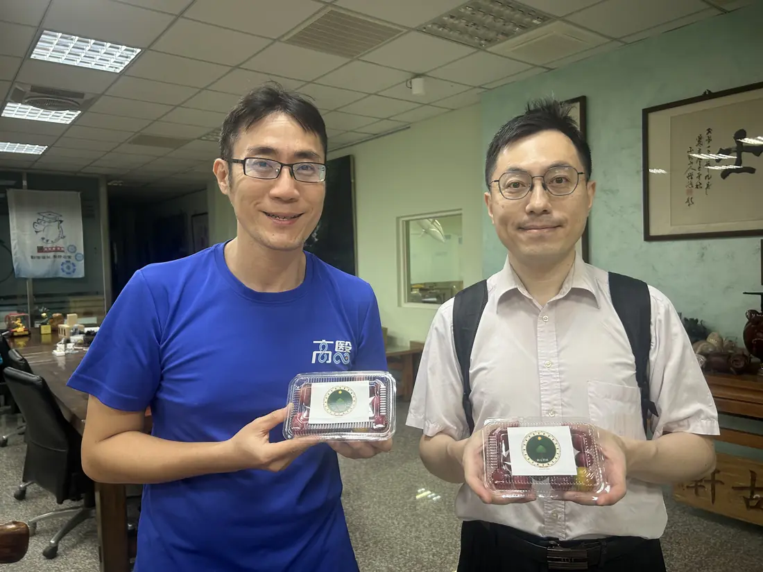 A friend who received red-flesh plums, smiling and holding a box with the Saluwan Farm label