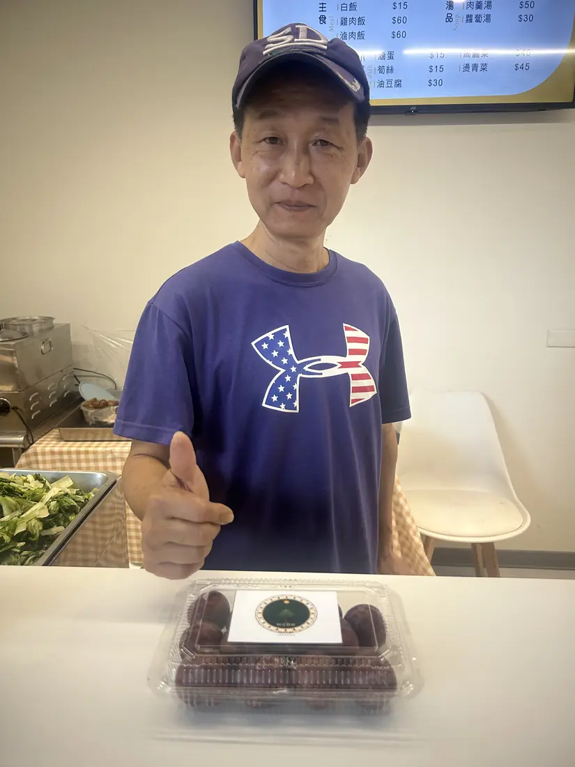 A friend who received red-flesh plums, smiling and holding a box with the Saluwan Farm label